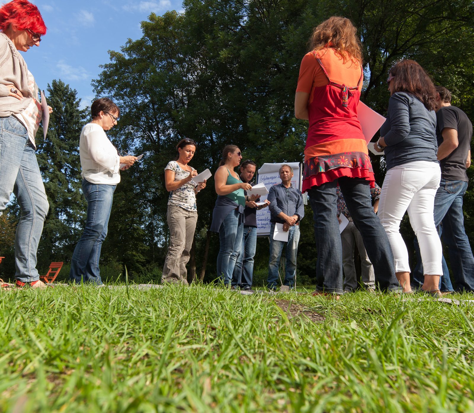 Teilnehmende einer Weiterbildung im Gespräch auf einer Wiese
