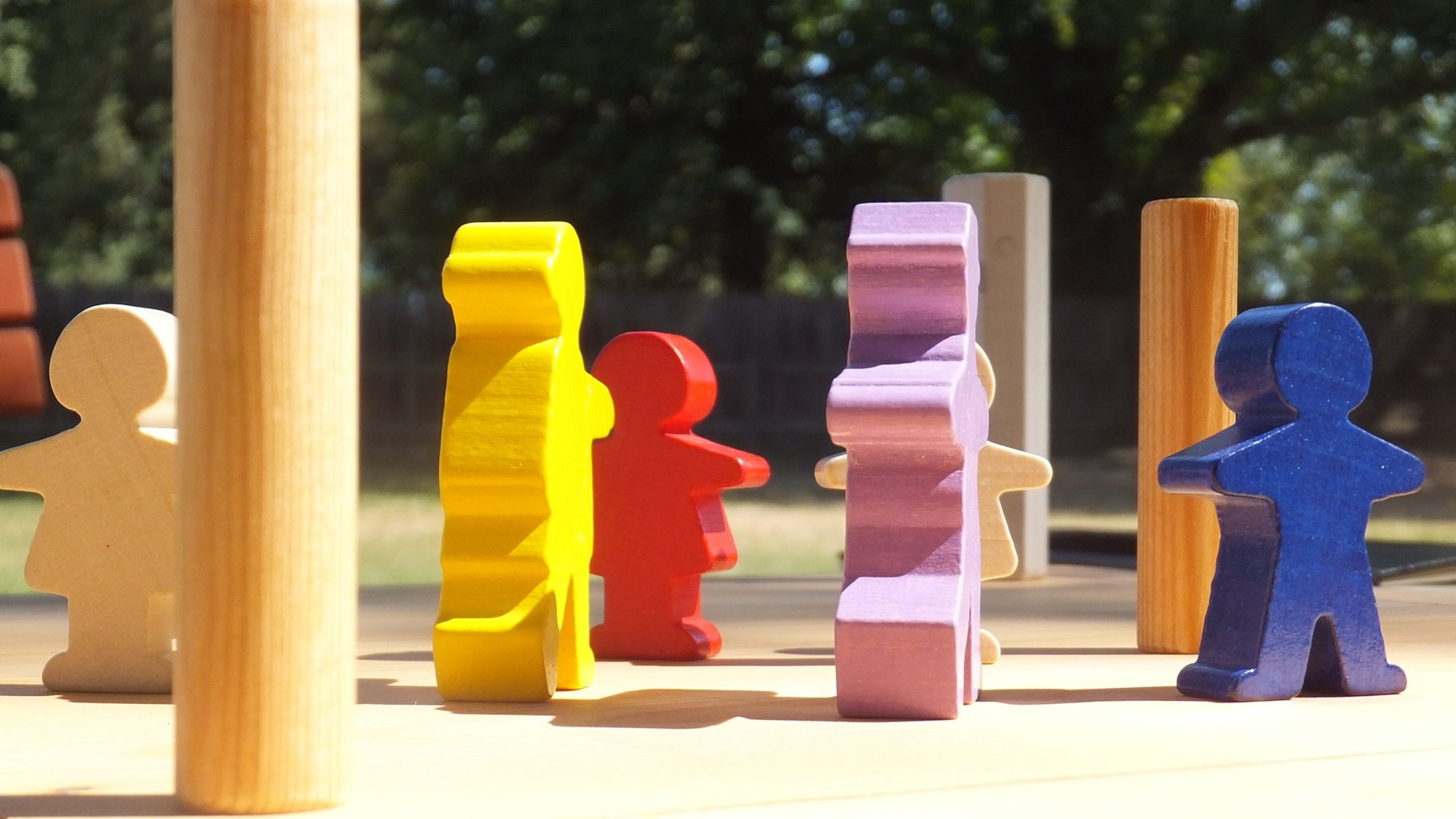 Bunte Holzfiguren als Aufstellung im Sonnenlicht