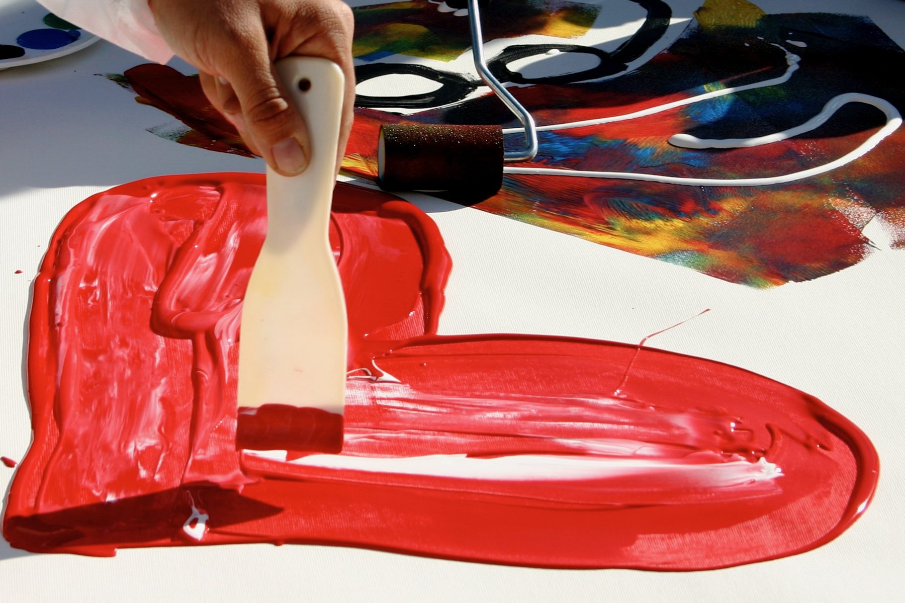 Hand zieht mit einem Spachtel rote Farbe zu einem Herz